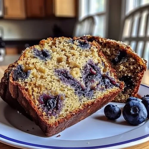 Freshly baked blueberry banana bread sliced on a wooden cutting board