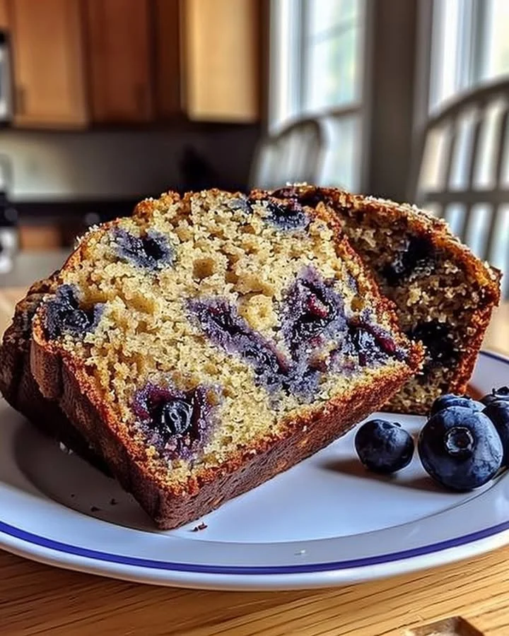 Freshly baked blueberry banana bread sliced on a wooden cutting board