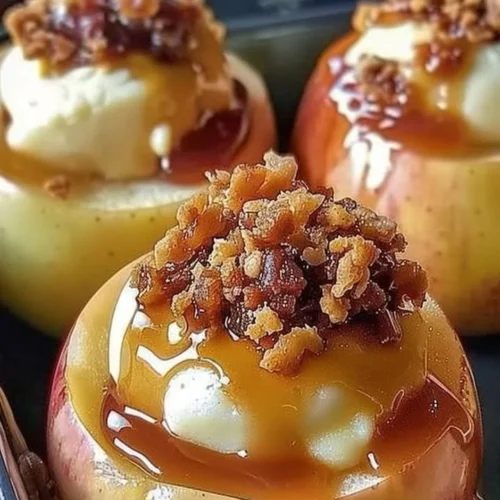 Cheesecake stuffed baked apples topped with caramel and nuts on a plate