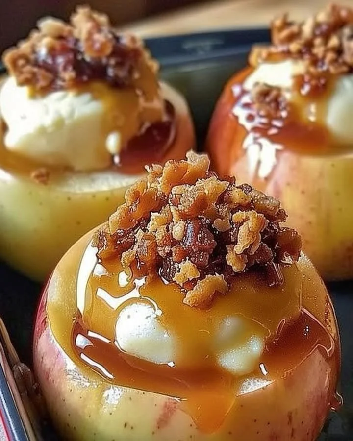 Cheesecake stuffed baked apples topped with caramel and nuts on a plate