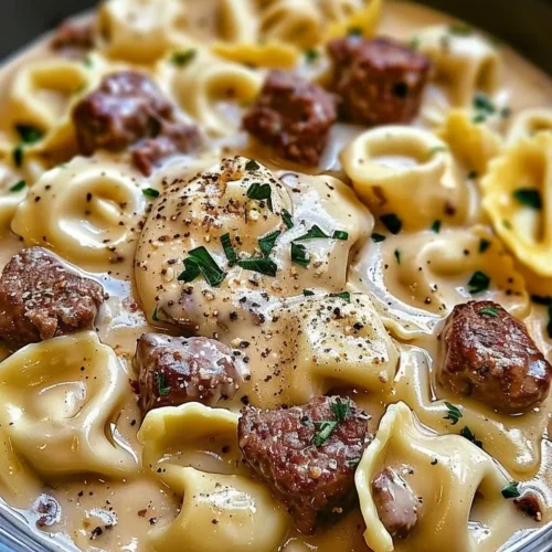 Cheesesteak Tortellini served in a creamy Provolone sauce topped with herbs