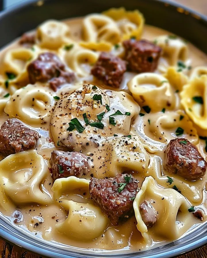 Cheesesteak Tortellini served in a creamy Provolone sauce topped with herbs