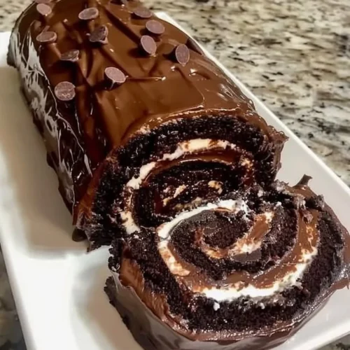 Delicious chocolate cake roll topped with whipped cream and chocolate shavings
