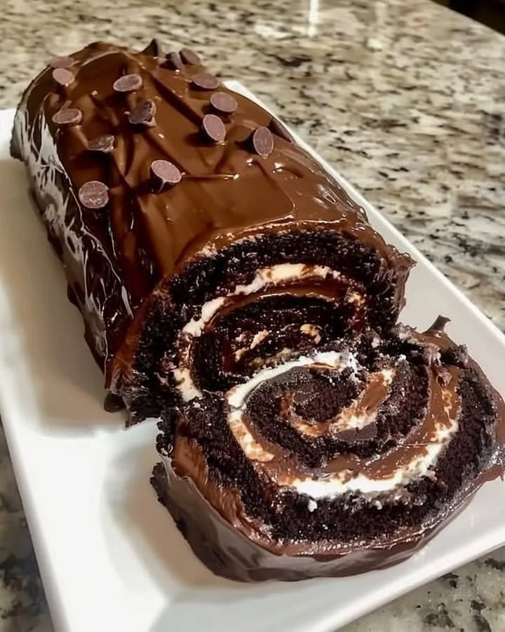 Delicious chocolate cake roll topped with whipped cream and chocolate shavings