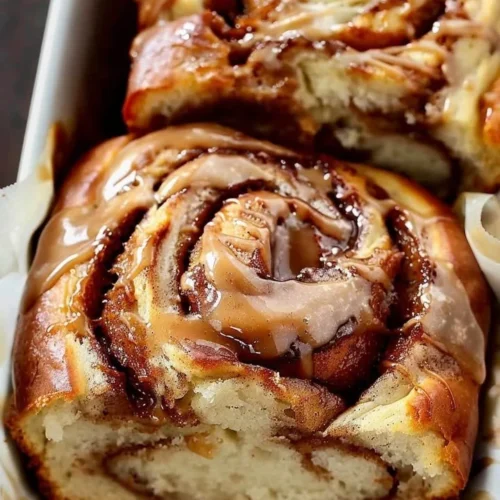 Sliced Cinnamon Swirl Bread on a wooden table with a sprinkle of cinnamon