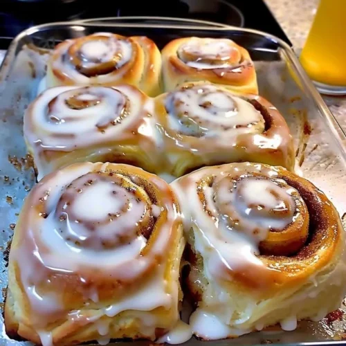 Classic cinnamon rolls topped with cream cheese frosting on a wooden table