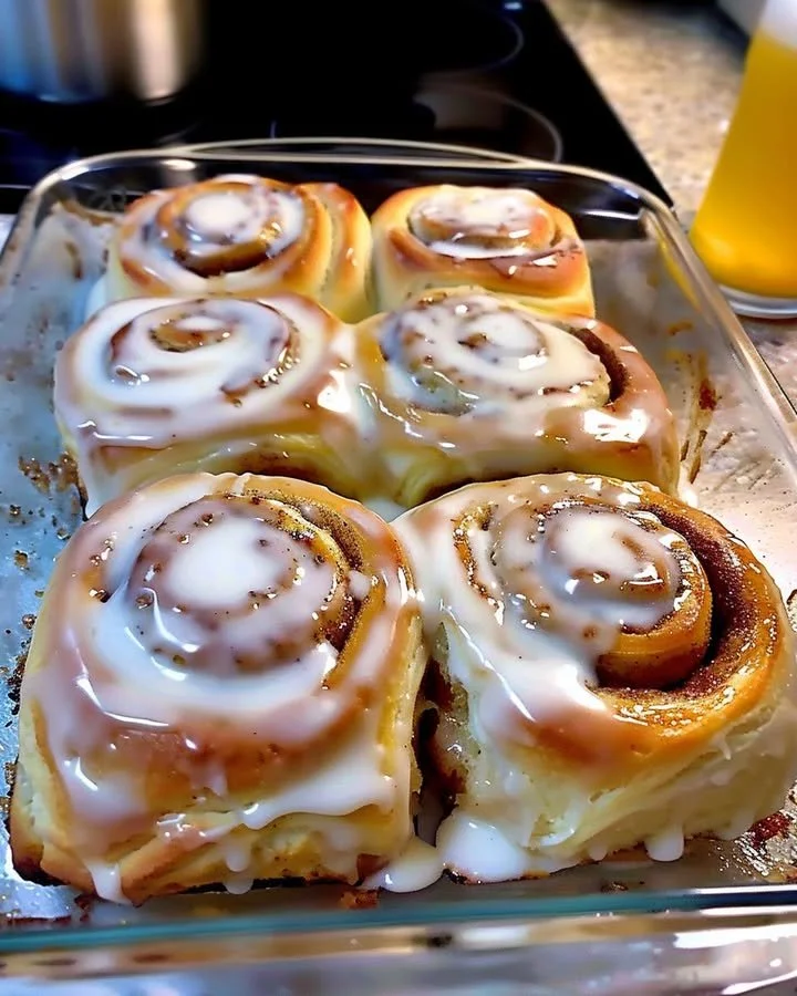 Classic cinnamon rolls topped with cream cheese frosting on a wooden table