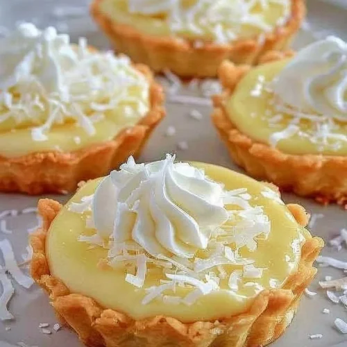 Delicious coconut cream tarts topped with whipped cream and toasted coconut flakes.
