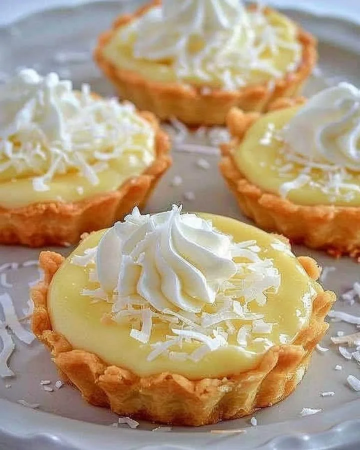 Delicious coconut cream tarts topped with whipped cream and toasted coconut flakes.