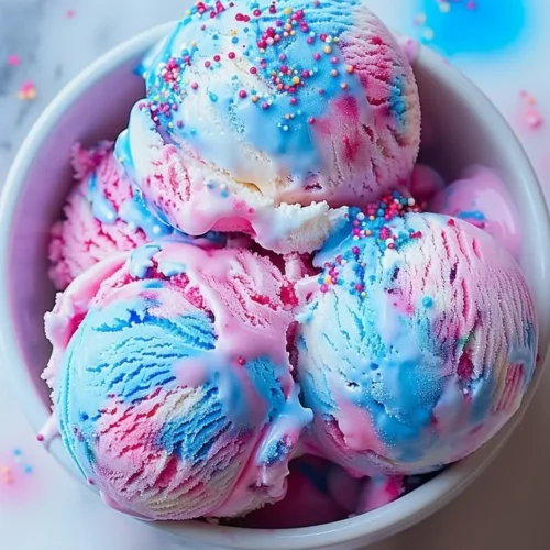 A colorful bowl of cotton candy ice cream topped with sprinkles.