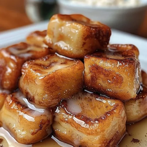Plate of crispy cinnamon roll French toast bites with maple glaze