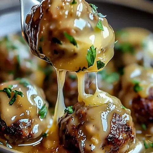 Crock Pot French Onion Meatballs served in a white bowl with melted cheese on top.