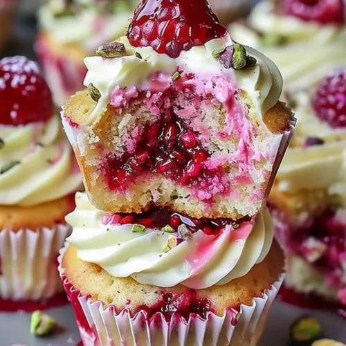 Fluffy raspberry pistachio cupcakes topped with creamy frosting and fresh raspberries