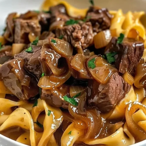 Delicious French onion beef and noodles in a bowl with melted cheese on top.