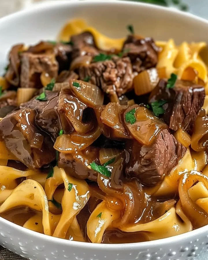 Delicious French onion beef and noodles in a bowl with melted cheese on top.
