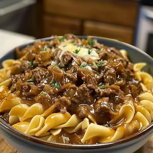 Delicious bowl of French Onion Beef and Noodles garnished with herbs
