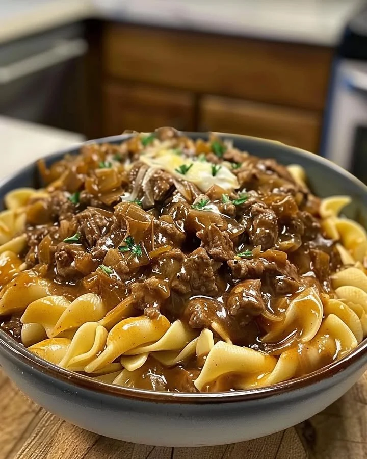 Delicious bowl of French Onion Beef and Noodles garnished with herbs