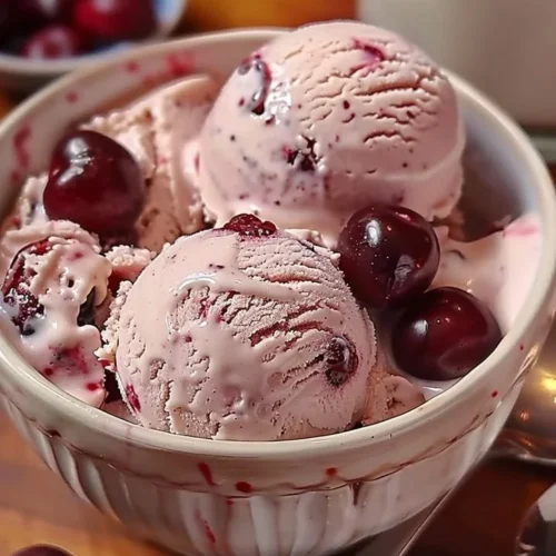 A bowl of homemade cherry vanilla ice cream topped with fresh cherries