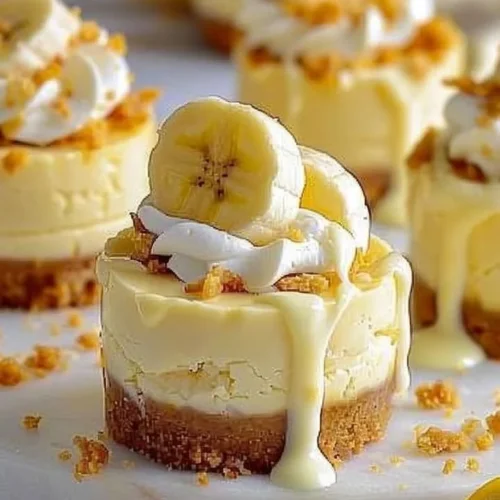 Mini banana pudding cheesecakes topped with whipped cream and banana slices.