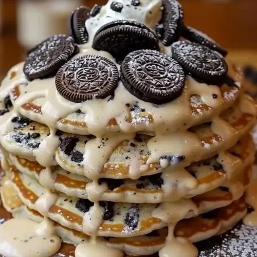 Oreo pancakes topped with cream cheese drizzle on a plate