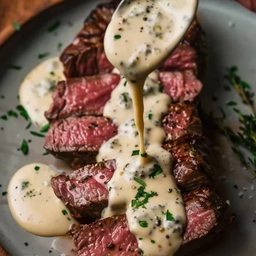 Pan-seared New York Strip Steak topped with Gorgonzola cream sauce served on a plate.