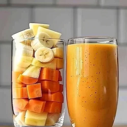 Pineapple Orange Carrot Smoothie in a glass with fresh ingredients around it.