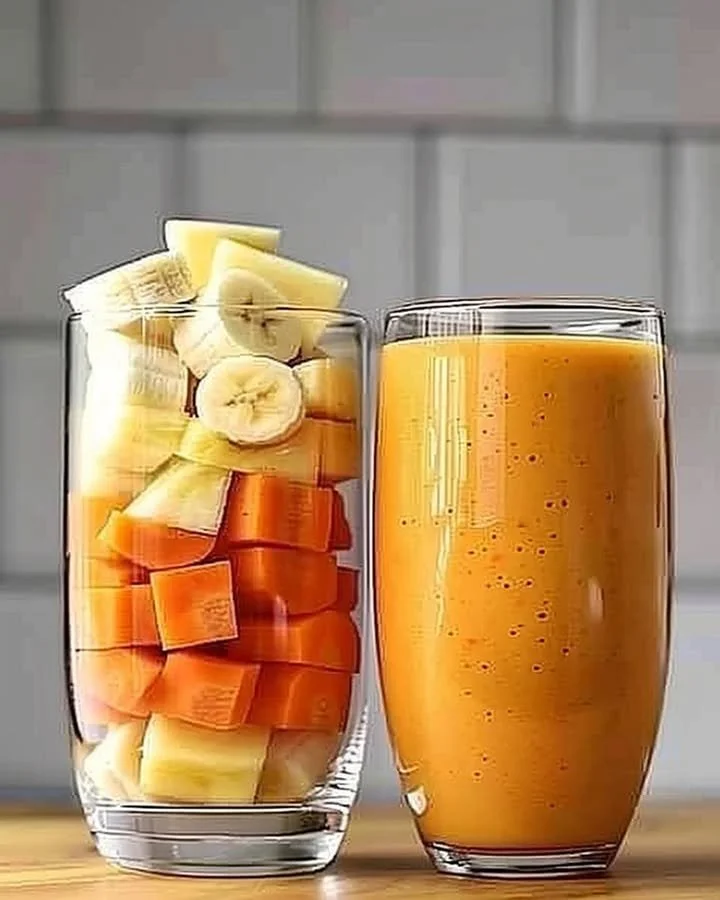 Pineapple Orange Carrot Smoothie in a glass with fresh ingredients around it.