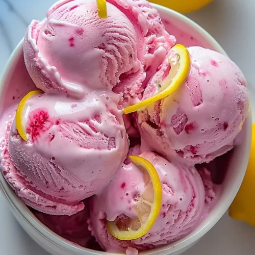 Homemade Pink Lemonade Ice Cream in a bowl garnished with fresh lemon slices