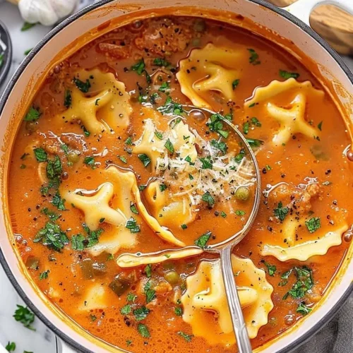 A bowl of delicious one pot ravioli soup garnished with herbs and cheese.