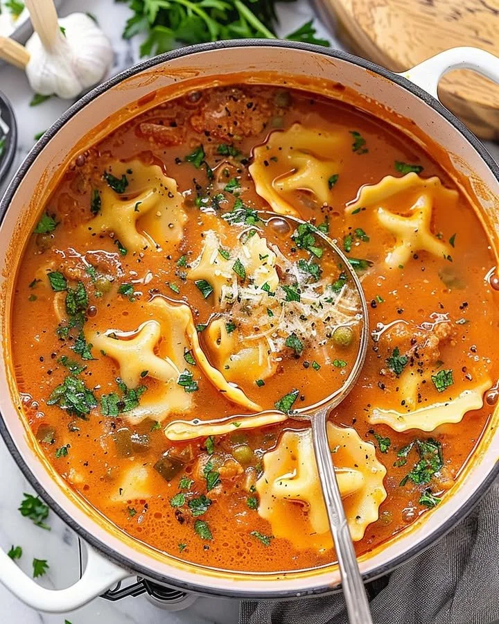 A bowl of delicious one pot ravioli soup garnished with herbs and cheese.