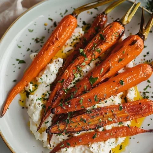 Roasted carrots topped with whipped feta cheese on a serving plate