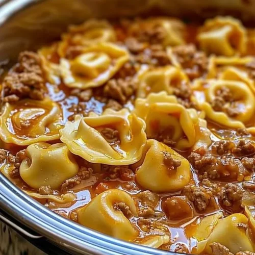 A delicious bowl of slow cooker cheesy tortellini topped with herbs.