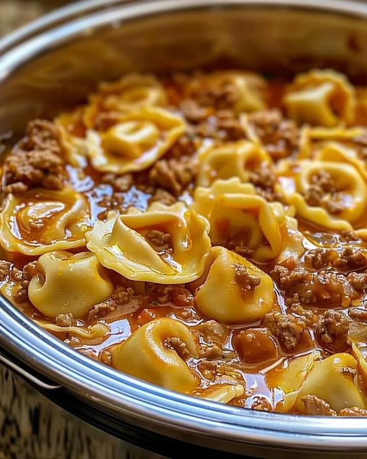 A delicious bowl of slow cooker cheesy tortellini topped with herbs.