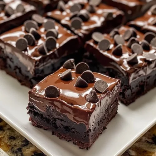 Decadent triple chocolate fudge brownies topped with chocolate ganache and nuts.