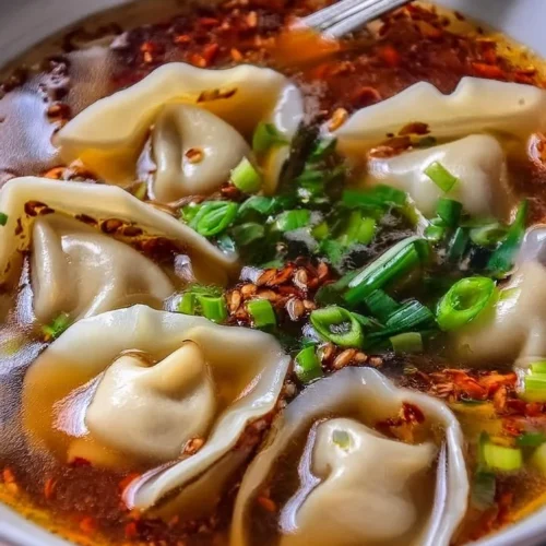 Bowl of homemade weeknight wonton soup with fresh herbs and vegetables