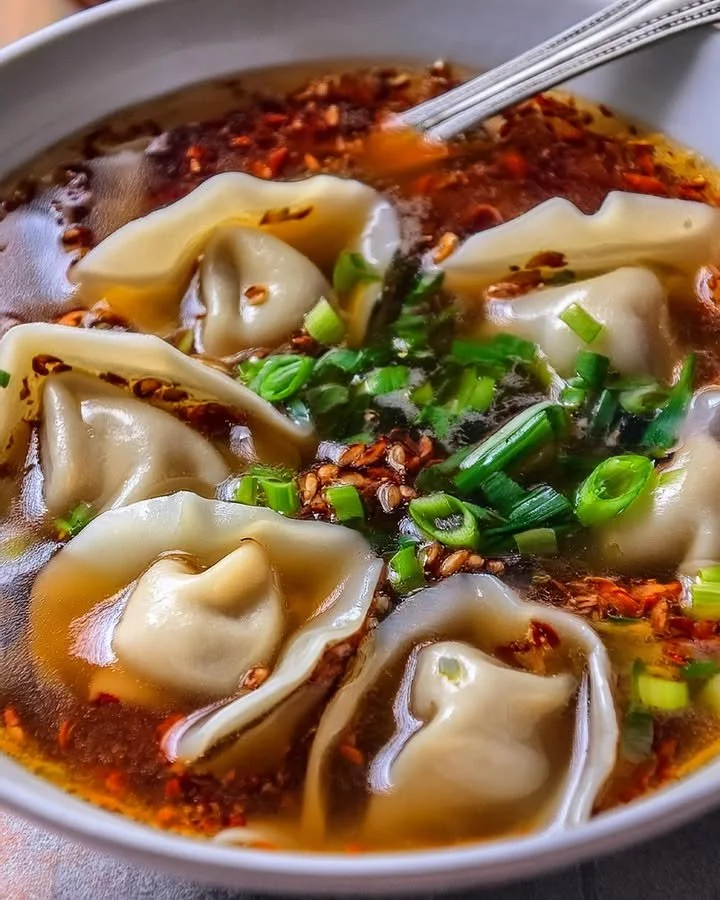 Bowl of homemade weeknight wonton soup with fresh herbs and vegetables