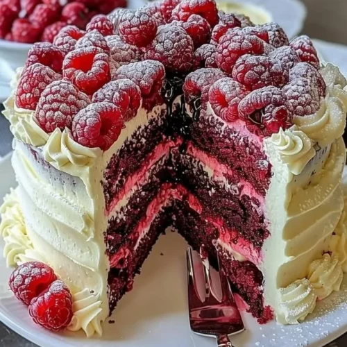 Slice of White Chocolate Raspberry Dream Cake topped with fresh raspberries